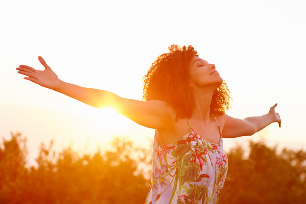 woman expressing freedom on a summer evening outdoors with her arms outstretched