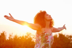 woman expressing freedom on a summer evening outdoors with her arms outstretched