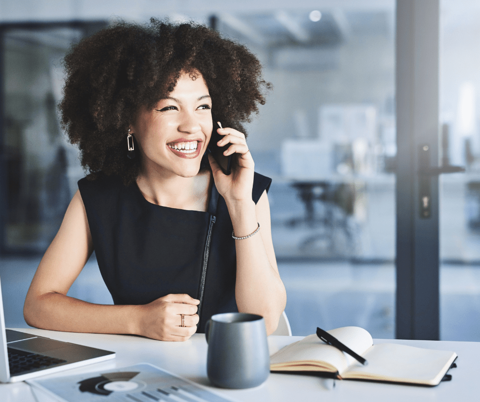 Trendy businesswoman smiling on phone at modern desk