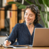 Woman on headset phone smiling taking notes