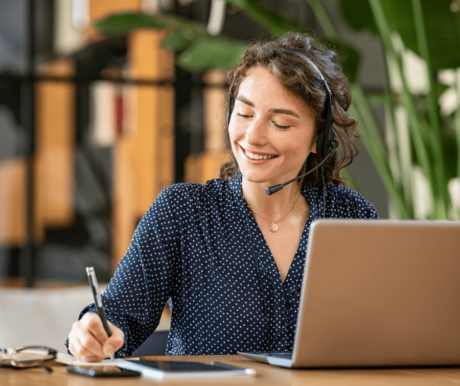 Woman on headset phone smiling taking notes