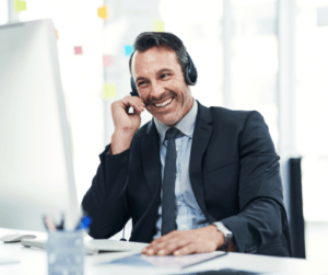 Businessman using headset phone smiling at computer
